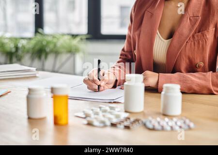 cropped african american nutritionist evaluating medication while writing notes in her office Stock Photo