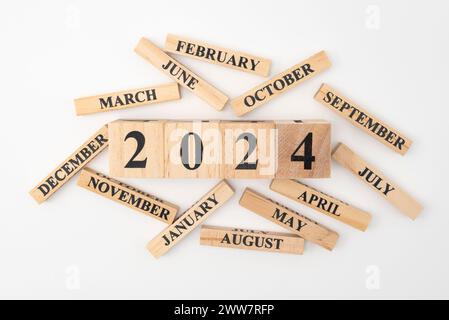 Wooden blocks and cubes with the year 2024 and the 12 months of the year randomly scattered around. Isolated on white background. Stock Photo