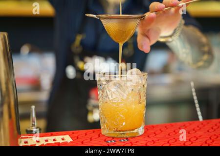 Bartender making a cocktail and pouring drink into a glass Stock Photo