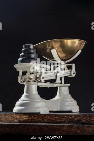 Classic weight scale Isolated on dark background. Old obsolete manual weighing scales and Iron Brass Tray with set of cast iron weights. Antique balan Stock Photo