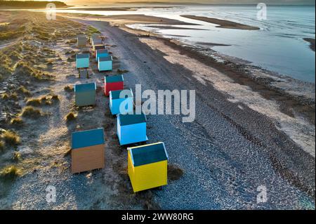 Findhorn Moray Coast Scotland a setting sun and a row of colourful beach huts looking towards the Black Isle Stock Photo