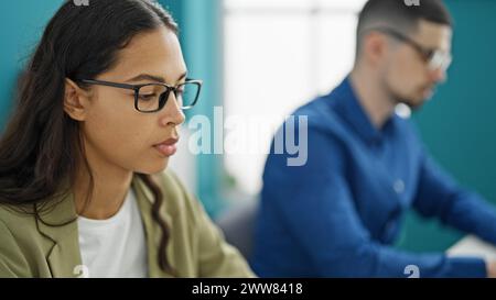 Two professional workers, man and woman, laser-focused on success, engrossed in their computer work, bonding as partners in the office interior Stock Photo