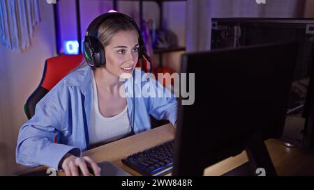 A focused young woman with headphones gaming at night indoors. Stock Photo