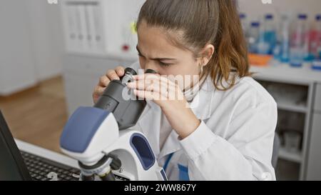 Young woman scientist using microscope in laboratory setting, showcasing research and healthcare. Stock Photo