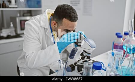 Hispanic scientist man analyzing samples using microscope in a laboratory setting Stock Photo