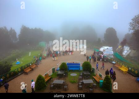 OOTY, INDIA - JANUARY 31 2023 Beautiful scenic view from dottabetta peak of green forest hill mountain with rain mist clouds background. Stock Photo