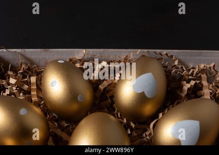 Close-up view of Gold eggs in paper box on black background. Stock Photo