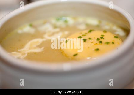 This image presents a bowl of creamy potato soup, its rich texture punctuated by a melting pat of butter and a sprinkle of fresh chives. Perfect for a comforting meal, the soup promises warmth and satisfaction with every spoonful. Culinary Comfort: Creamy Potato Soup Garnished with Chives. High quality photo Stock Photo