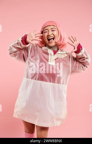 cheerful asian woman with pink hair and makeup happy laughing with hands on vibrant background Stock Photo