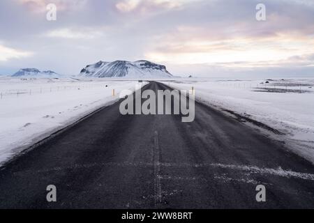 Empty road during winter in Iceland covered in snow during sunrise Stock Photo