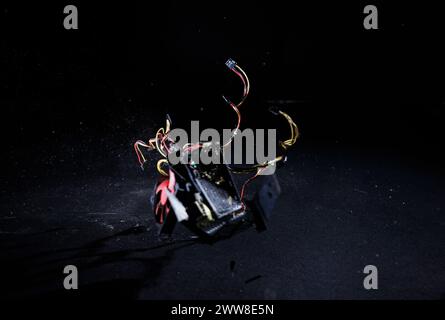 Male hands hitting hard PC power supply on the floor, demolishing and breaking PSU, isolated on a black background, slow motion shot. Computer Stock Photo