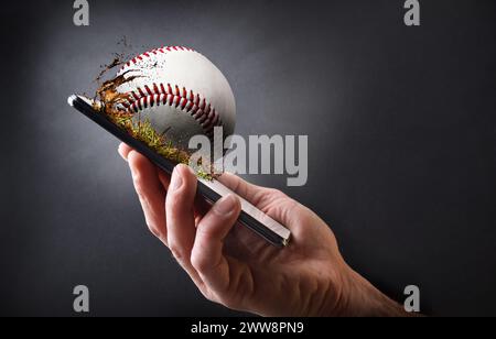 Concept of watching baseball online with hand holding a mobile phone with ball and dark gray isolated background. Stock Photo