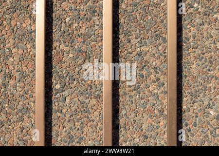 Concrete and pebble wall background with bronze metal bars Stock Photo