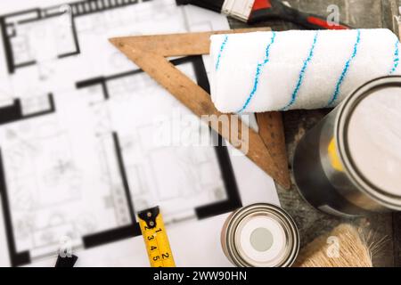 Plan of renovation of house on old wooden table. Top view. Sheet of paper with cans of paint and brushes, palette for choosing colors, construction le Stock Photo