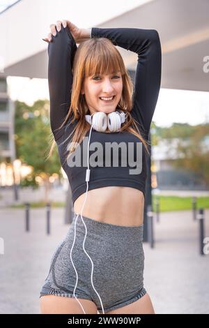 Vertical portrait smiling runner warming up stretching for running or doing cardio exercise. Stock Photo