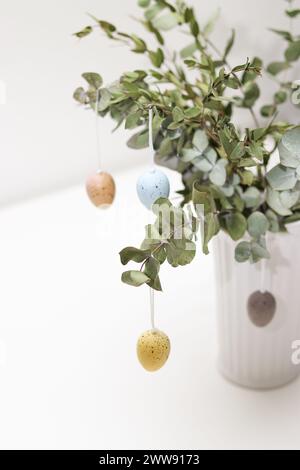 Colorful easter eggs hanging decorative on eucalyptus plant in a vase  Stock Photo