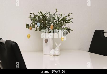 Easter decorations with bunnies and colorful eggs hanging on eucalyptus plant in a vase Stock Photo