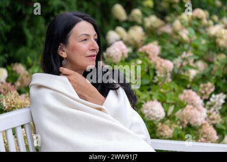 A mature woman, wrapped warmly, gazes into the distance, her expression one of peaceful self-acceptance during the life transition of midlife. High qu Stock Photo