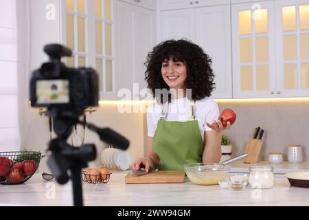 Smiling food blogger explaining something while recording video in kitchen Stock Photo