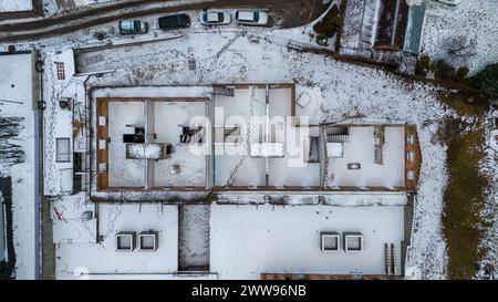 Drone photography of unfinished and abandoned building in a city covered by snow during winter cloudy day Stock Photo