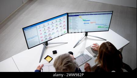 Employee Working On Calendar Schedule And Staff Time Sheet Stock Photo