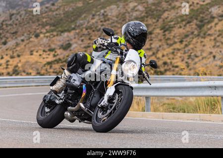 A man sits on his motorcycle and riding on a curving road, photograph taken on August 22, 2020 in the province of Avila, Spain, called the port of Nav Stock Photo