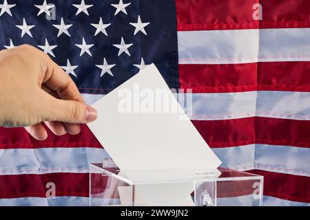 Hand putting his vote into ballot box against national flag of United States Stock Photo