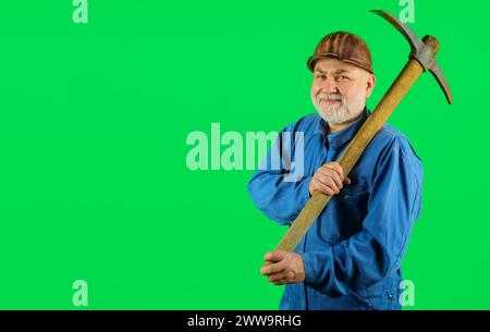 Smiling miner in uniform with pickaxe. Construction and building works. Bearded construction worker or craftsman in hard hat with pick-axe. Male Stock Photo