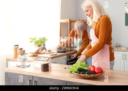 Mature female friends cooking in kitchen Stock Photo