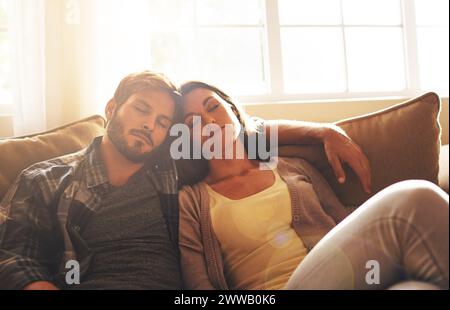 Sleeping, tired and couple on sofa to relax with sunshine for resting, comfortable and dreaming in home. Marriage, dating and man and woman on couch Stock Photo
