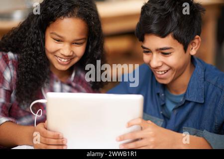 Students, boy and girl with tablet in classroom for elearning, educational video and online assessment with smile. School kids, friends and happy with Stock Photo