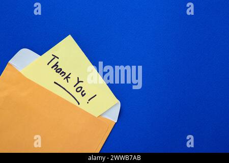 Thank you note on yellow paper in an envelope. Thank you message Stock Photo