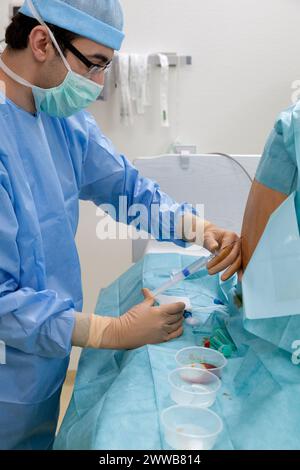 Epidural. Anesthesiologist injecting the analgesic cocktail into the ...
