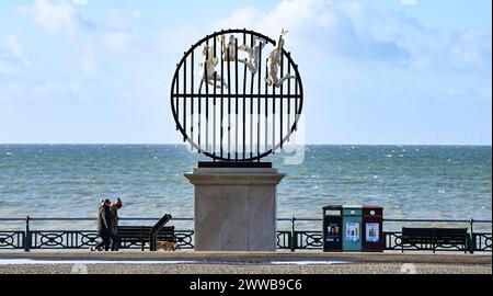 Brighton UK 23rd March 2024 -  Dog walkers pass by the Flight of the Langoustine sculpture on Hove Plinth on the seafront on a sunny but chilly morning along the South Coast .  The sculpture was created by Brighton based sculptor Pierre Diamantopoulo and is the second to adorn Hove Plinth : Credit Simon Dack / Alamy Live News Stock Photo