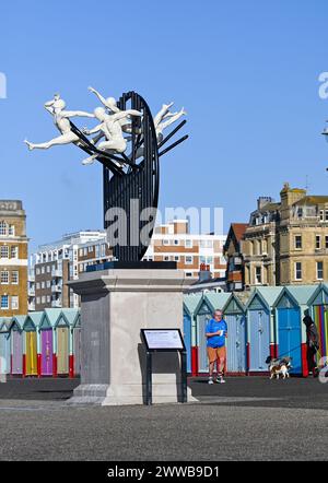 Brighton UK 23rd March 2024 -  Runners pass by the Flight of the Langoustine sculpture on Hove Plinth on the seafront on a sunny but chilly morning along the South Coast .The sculpture was created by Brighton based sculptor Pierre Diamantopoulo and is the second to adorn Hove Plinth : Credit Simon Dack / Alamy Live News Stock Photo