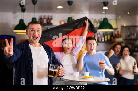 Enthusiastic German fans scream with joy in beer bar. Germany victory Stock Photo