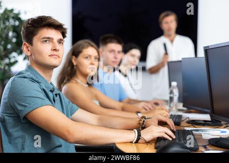 Guy with group of students listening to lecture in computer classroom Stock Photo