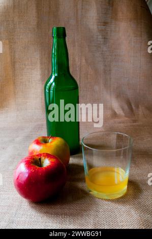 Glass and bottle of cider with two apples. Asturias, Spain. Stock Photo