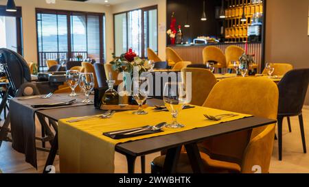 A restaurant scene with yellow tablecloths, glassware, and cutlery. Stock Photo