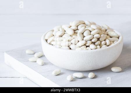 Uncooked dried white haricot beans in bowl or spoon on table. Heap of legume haricot bean background ( Phaseolus vulgaris ) Stock Photo