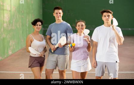 Two happy couples after playing paleta fronton on tennis court Stock Photo