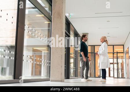 Doctor talking to man in hospital corridor Stock Photo