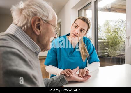 Home caregiver taking pulse of senior man Stock Photo