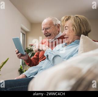Happy senior couple using tablet PC in living room at home Stock Photo