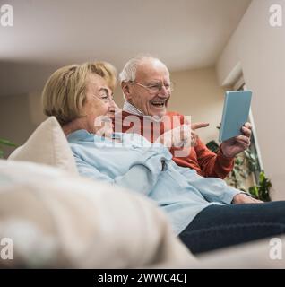 Cheerful senior couple using tablet PC in living room at home Stock Photo