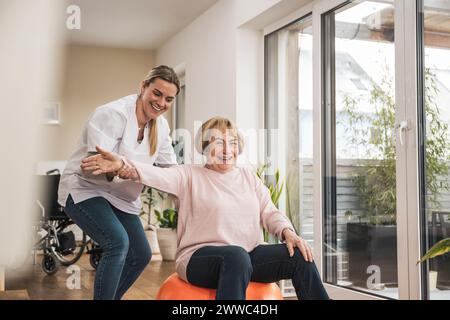 Happy home caregiver with senior woman doing exercise Stock Photo
