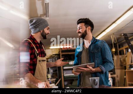 Smiling young carpenters discussing with each other at workshop Stock Photo