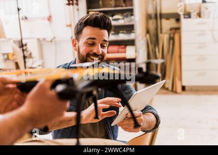 Happy engineer programming drone with tablet PC at workshop Stock Photo