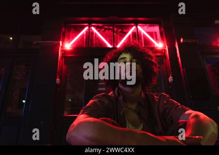 Young man sitting near illuminated structure Stock Photo