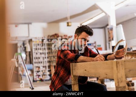 Carpenter working with wooden object at table in workshop Stock Photo